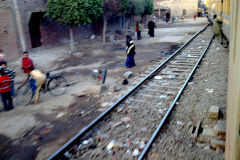 People jump in front of the train station from the train in El Wasta, Egypt